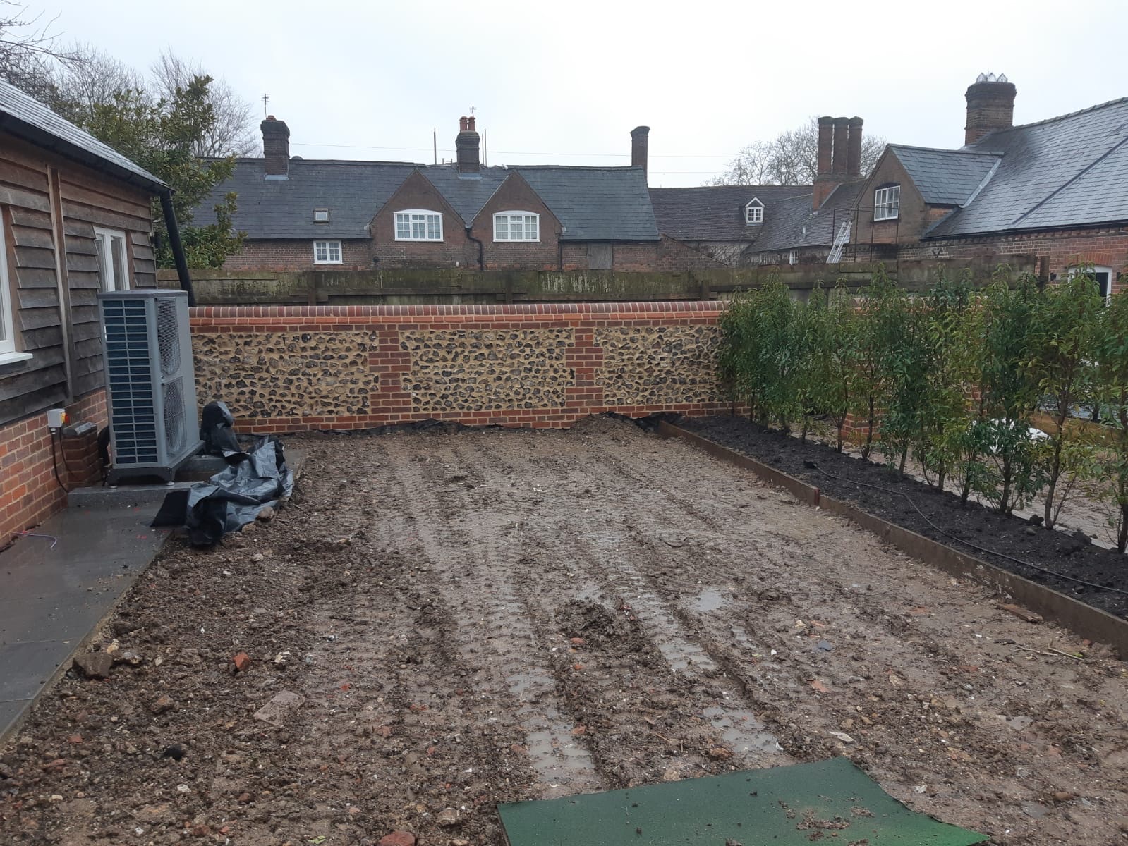 Long flint and brick boundary wall with estate buildings behind