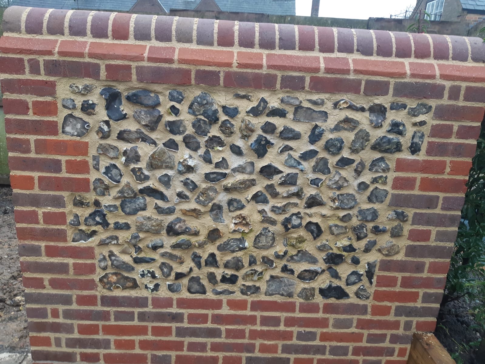 Close-up of traditional flint panel set in red brick wall